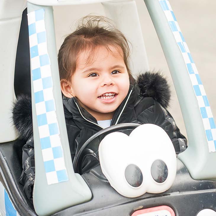 Little girl in toy police car