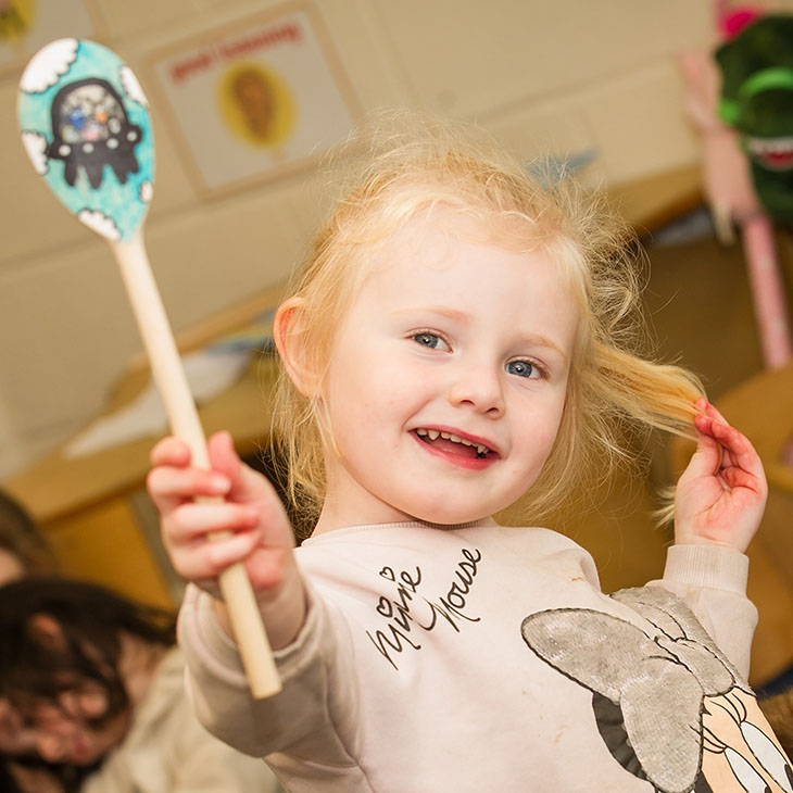 Girl holding up a painted wooden spoon
