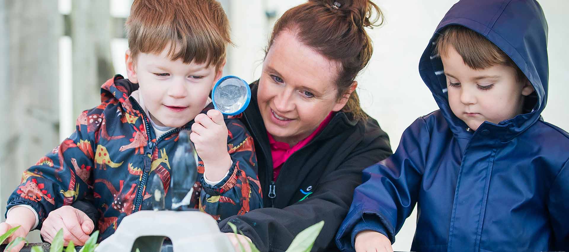 Boy  holding magnifying glass up to look at nature