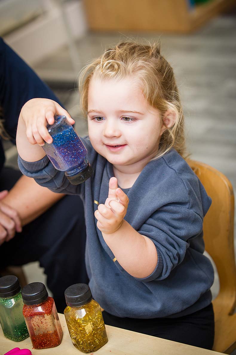Little girl holding up a pot of glitter paint