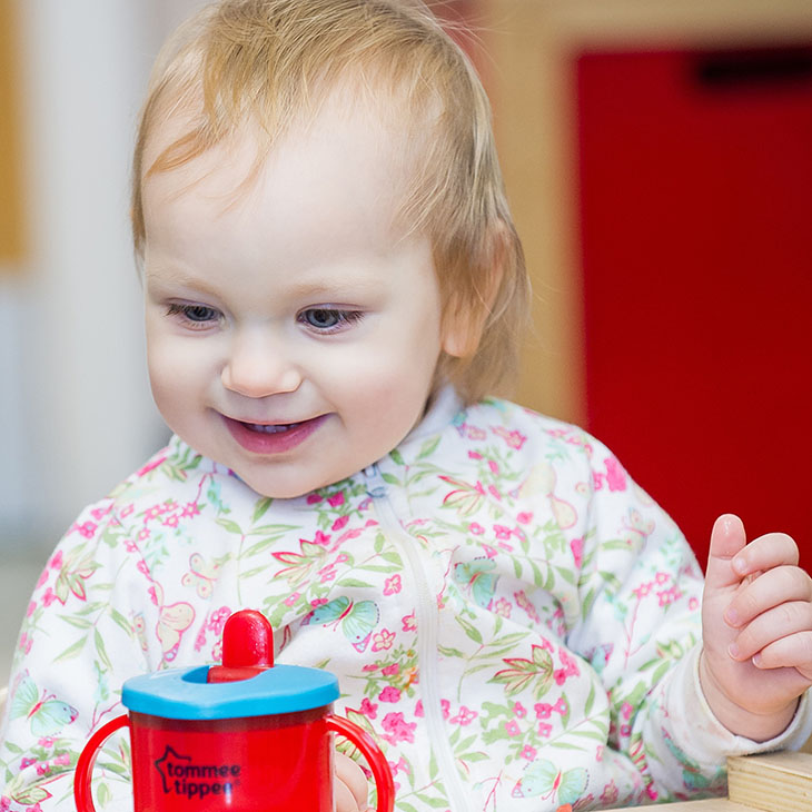 Smiling toddler with a plastic drinking cup