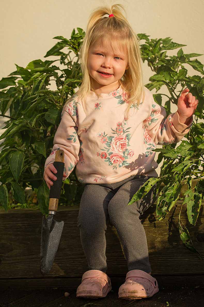 Little blonde girl holding a gardening trowel