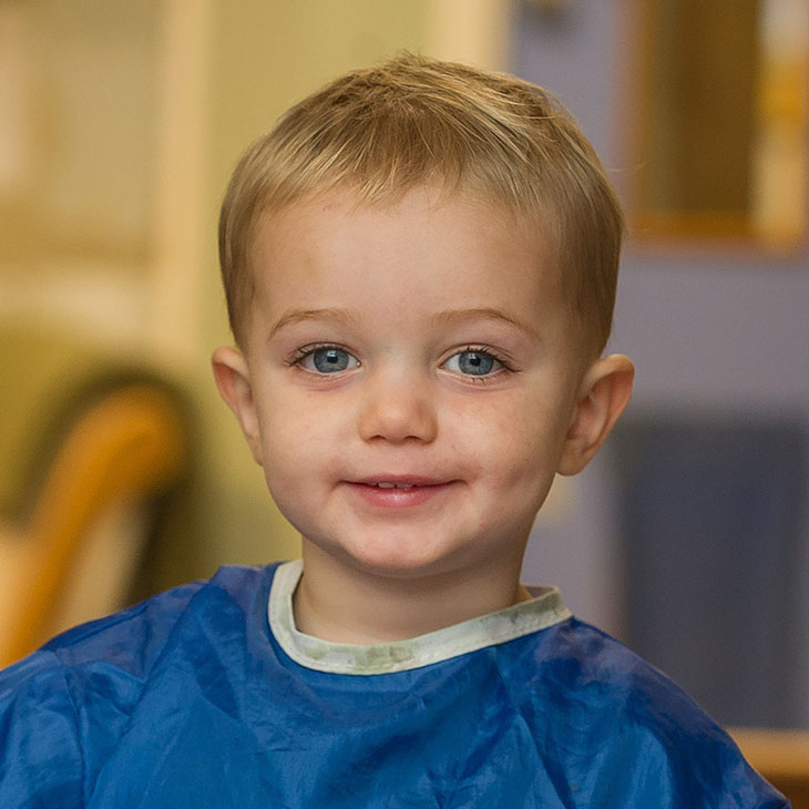 Smiling boy with blue eyes wearing a painting overall