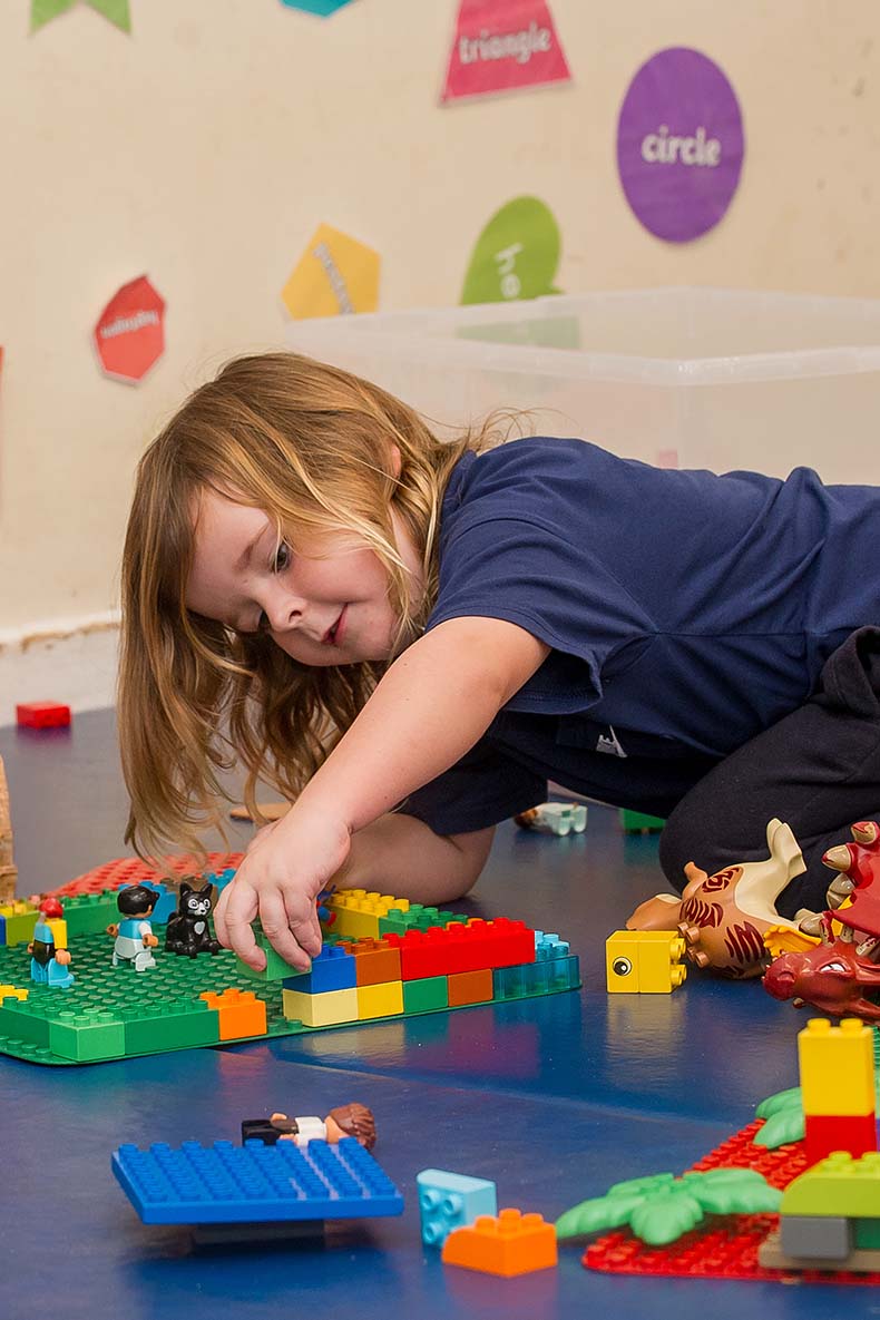 Little girl on the floor playing with lego