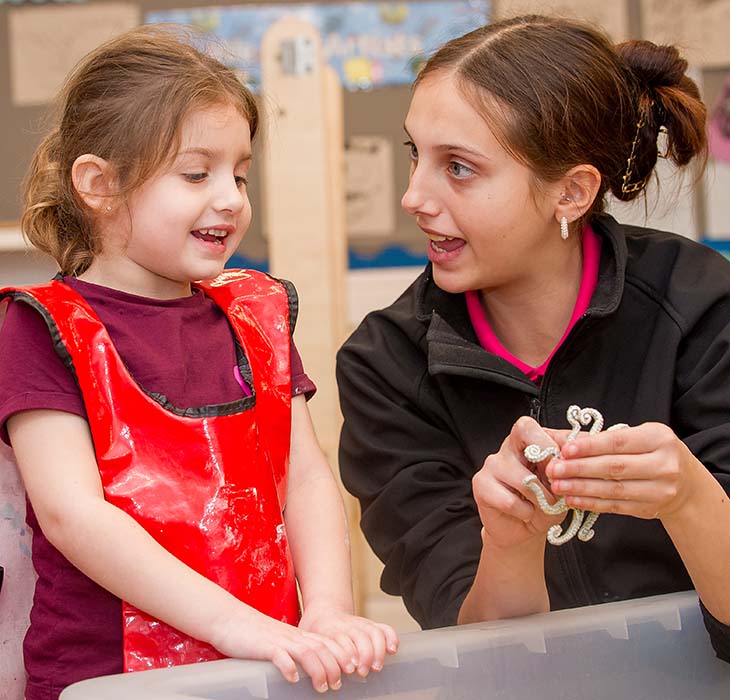 Teacher talking to girl with an apron on