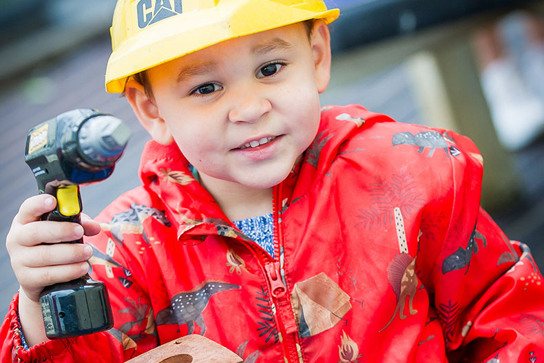 Little boy with toy drill and hard hat at Keystone Nursery