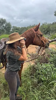 Looking for wildlife with binoculars beside a horse.