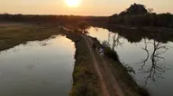 Riders beside the water beneath a setting sun.