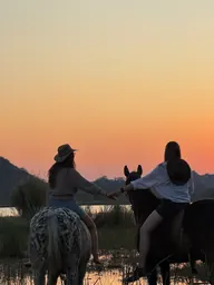 Two riders sharing a sunset beside the water