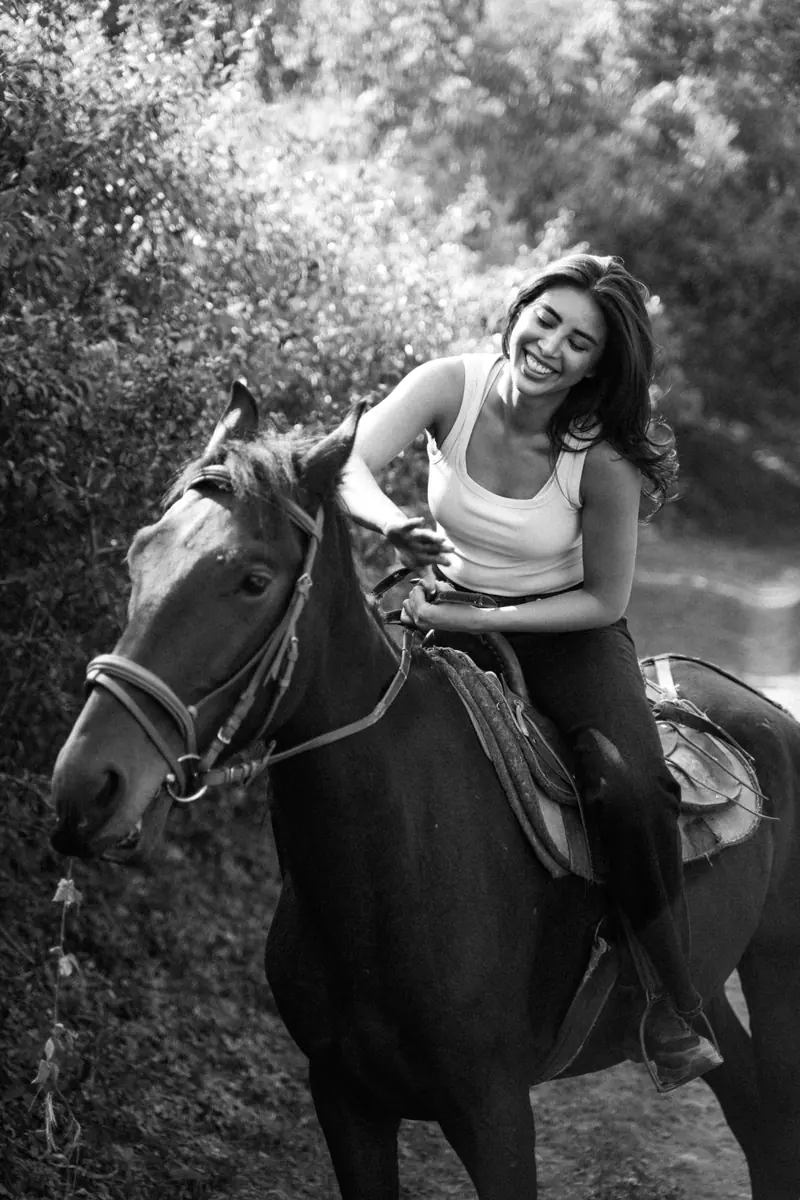 A black-and-white portrait of a smiling rider and her horse.
