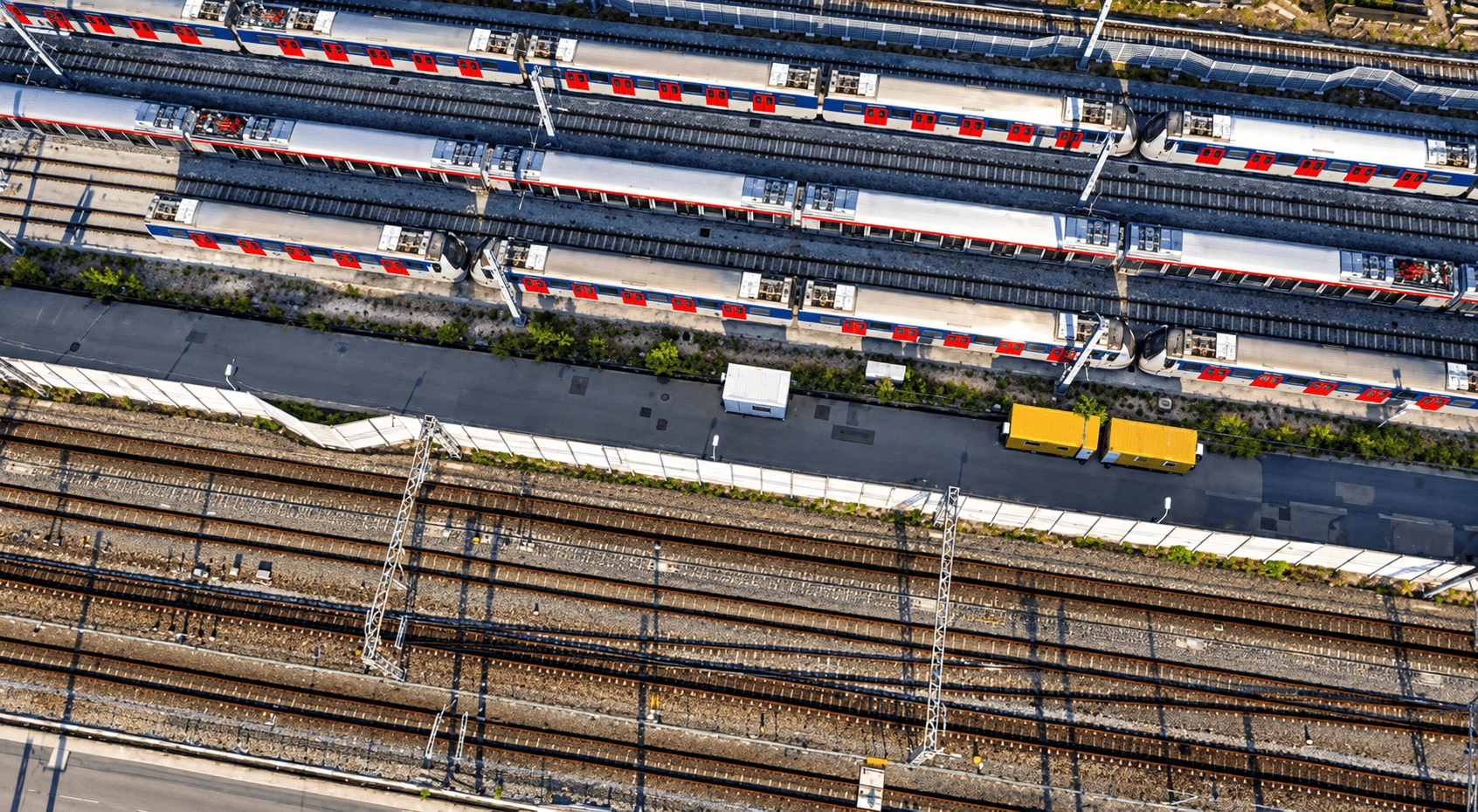 Aerial drone view of multiple railway tracks with solar panels installed alongside the tracks.