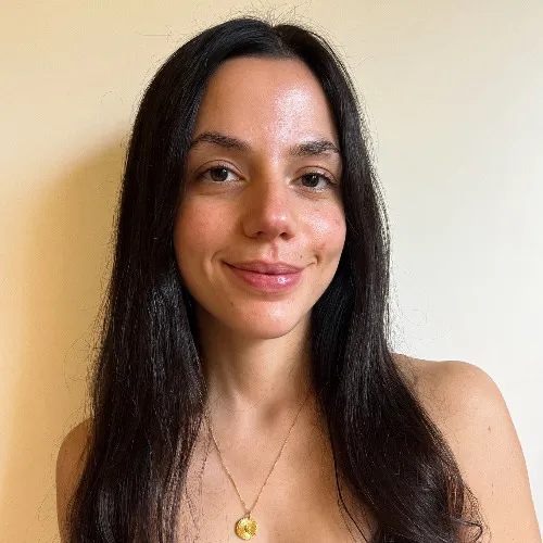 Laeticia Donini, CAMOH instructor, Woman with long dark hair smiling gently against a plain beige background.