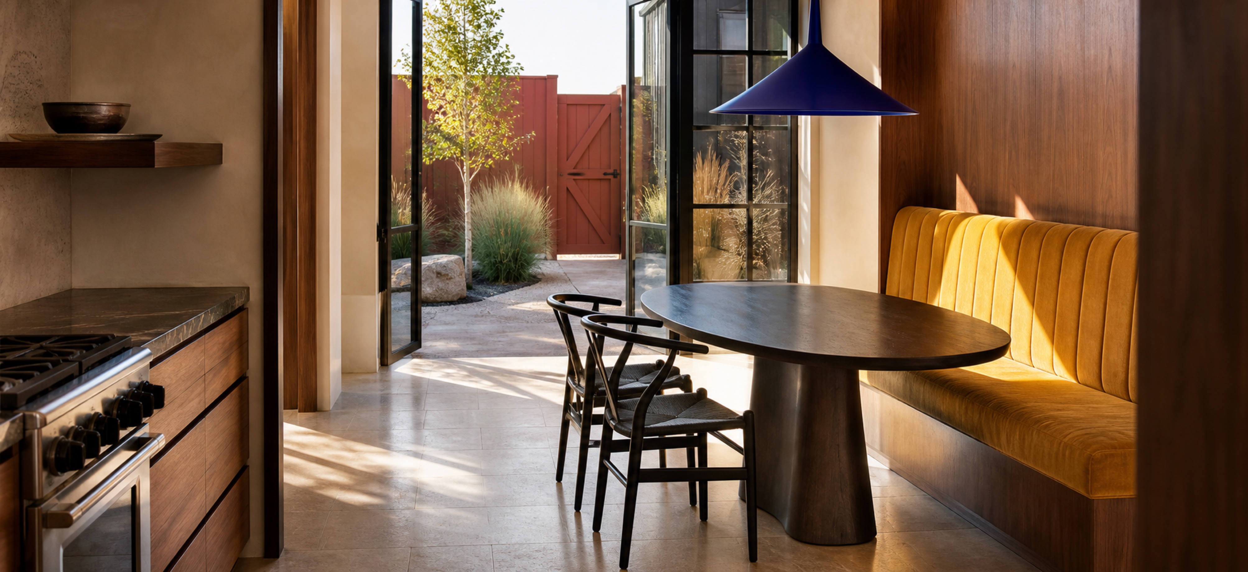 Ochre dining banquette and cobalt pendant in a contemporary Front Range dining nook with a red garden gate