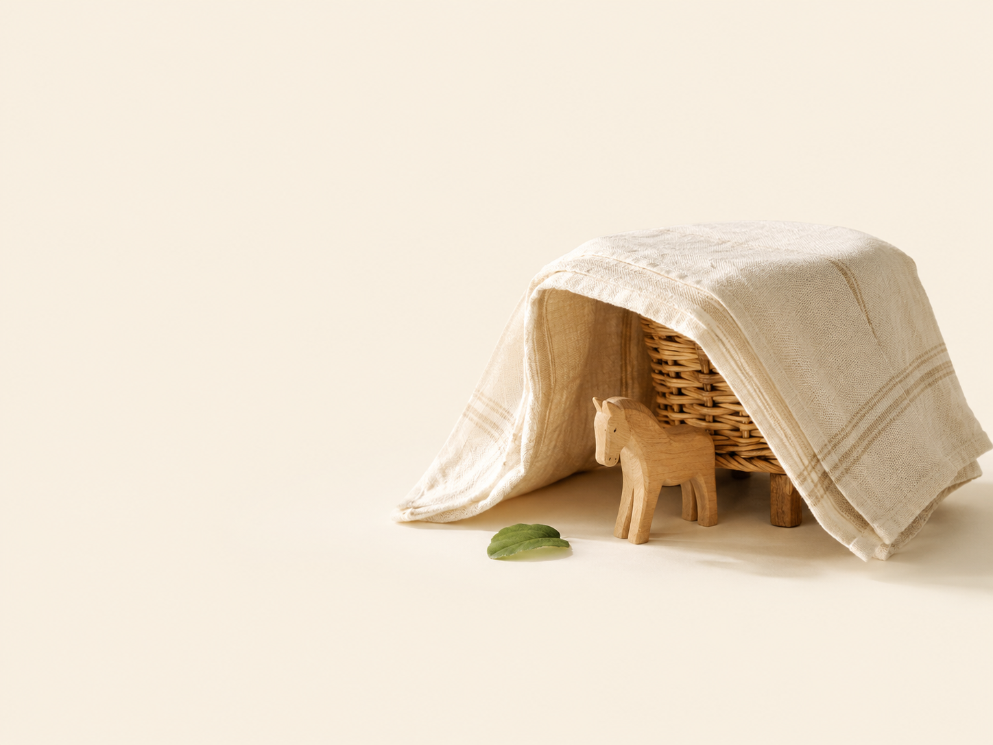 A tiny wooden horse resting under a simple linen shade shelter