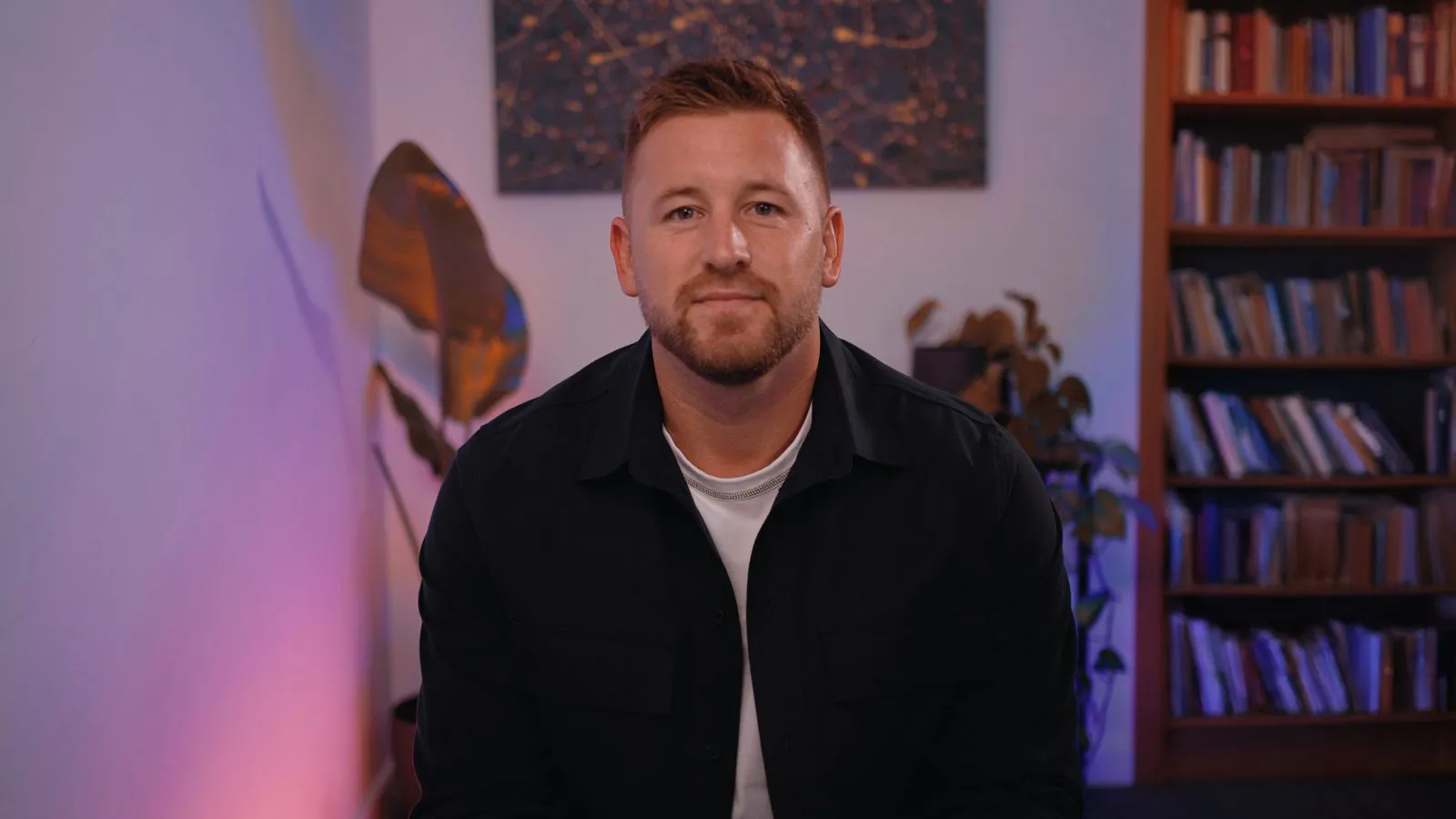 A man sitting in front of a book shelf.