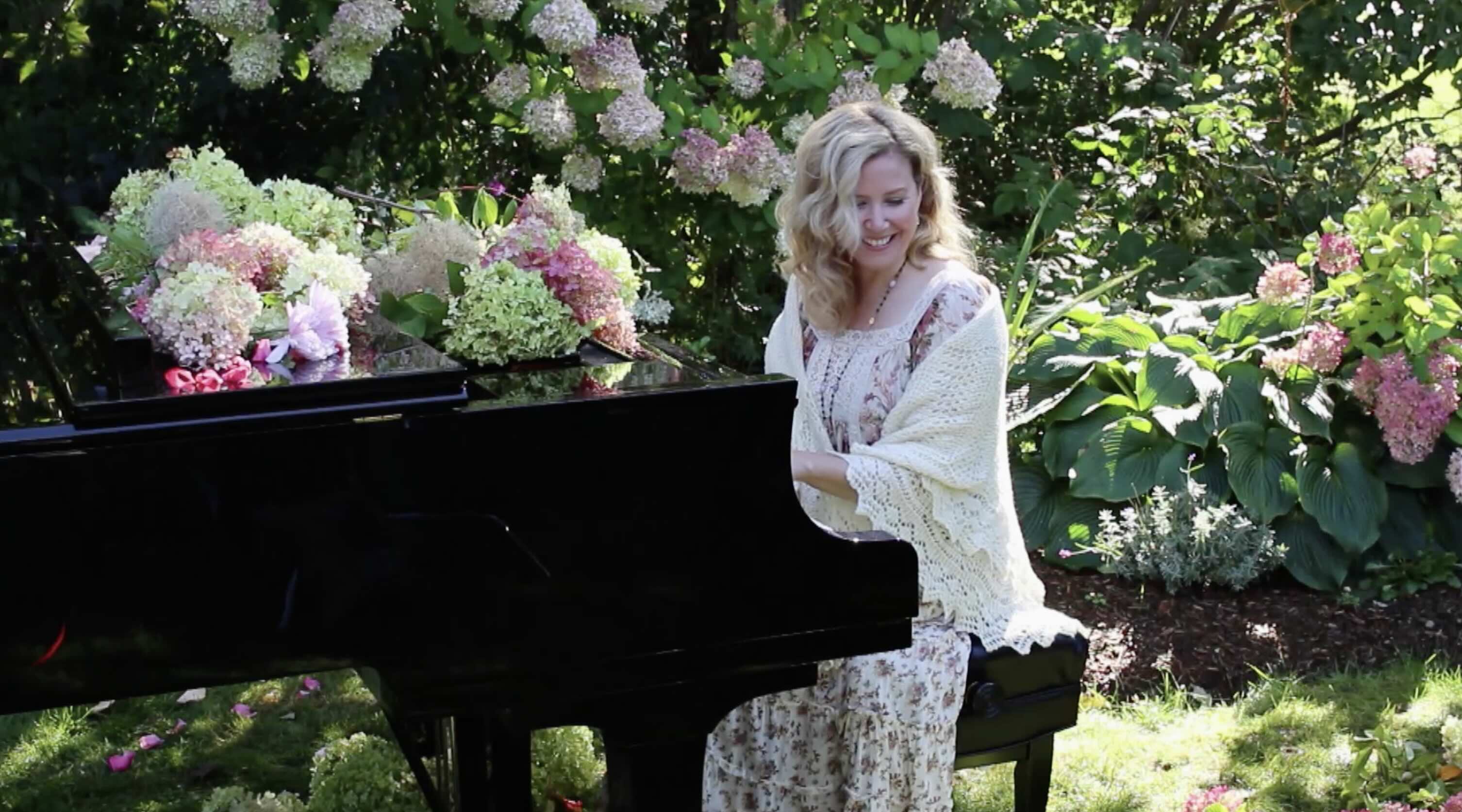 Branding video still image woman sitting at grand piano surrounded by her lovely garden