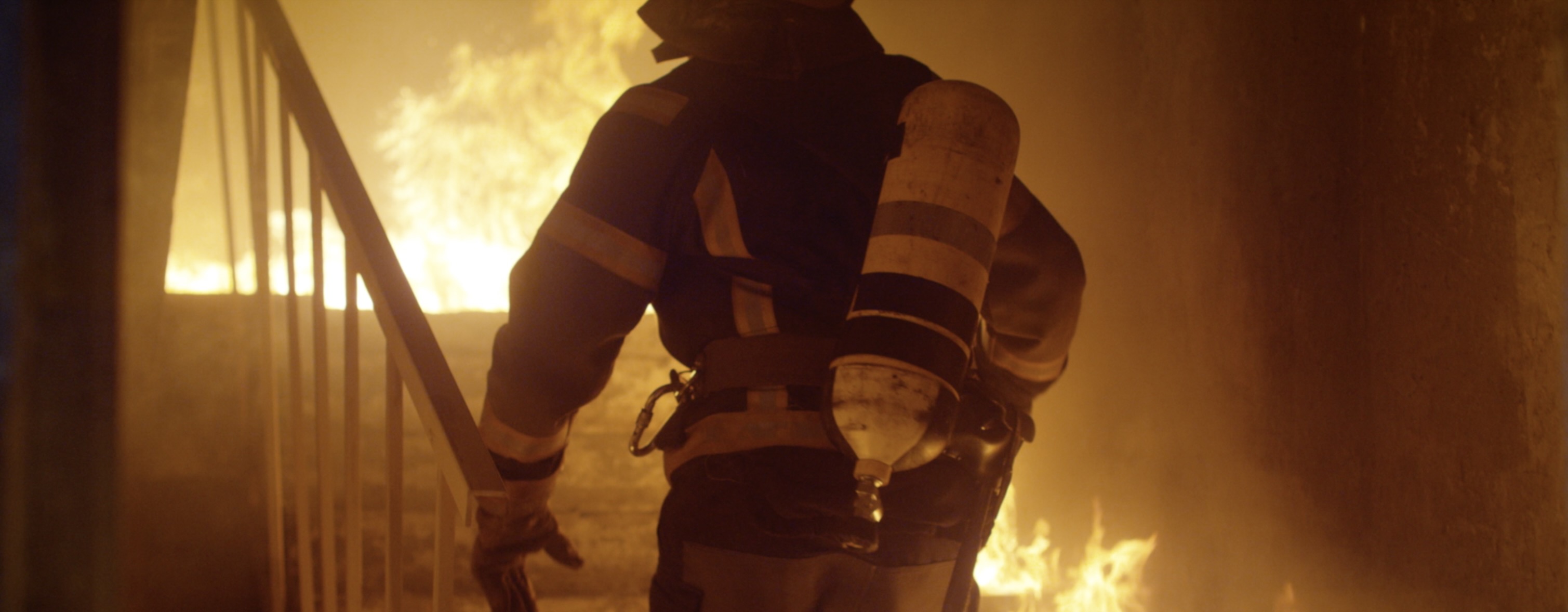 Cinematic image firefighter approaching steps of burning building