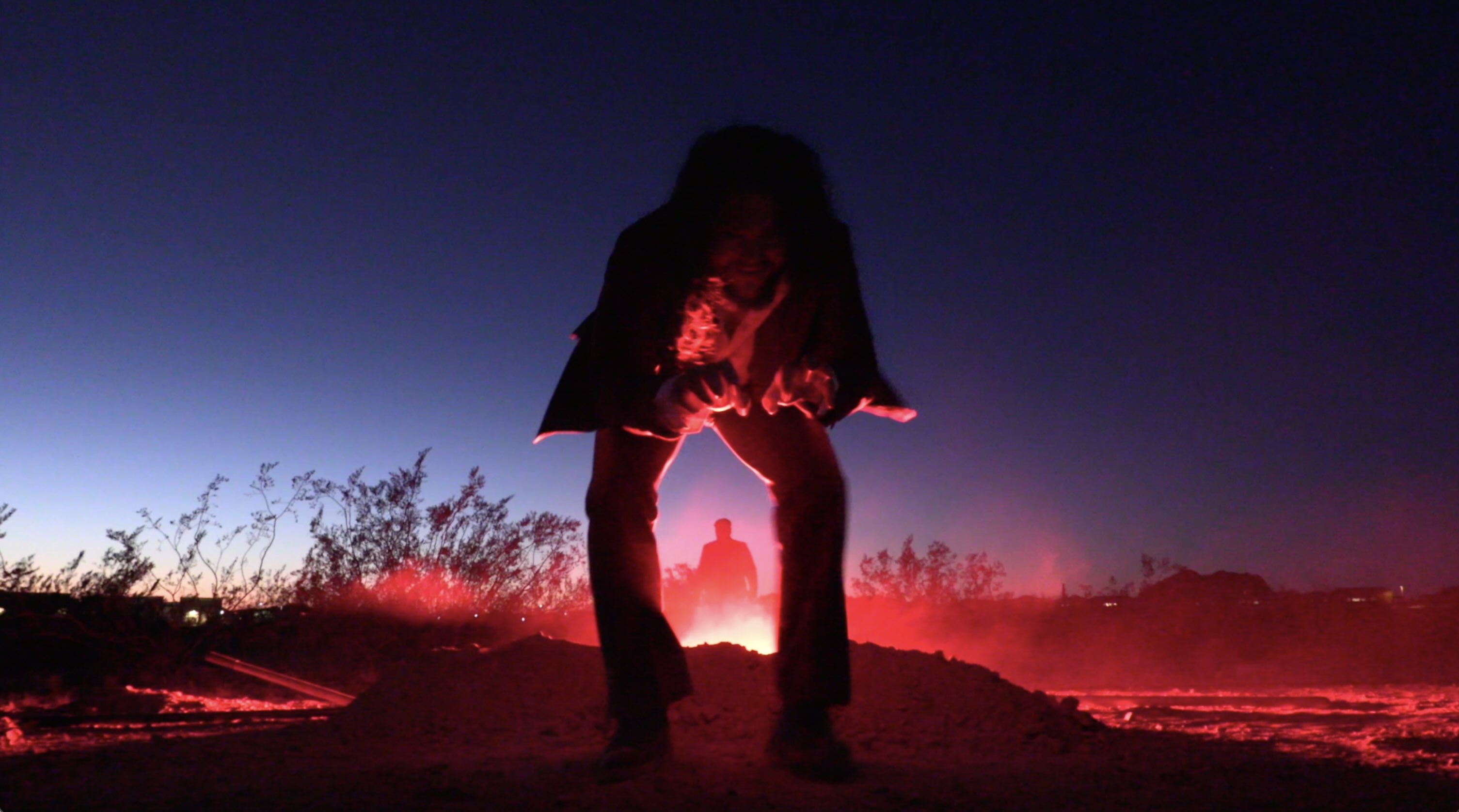 Figure standing against glowing red desert horizon at dusk