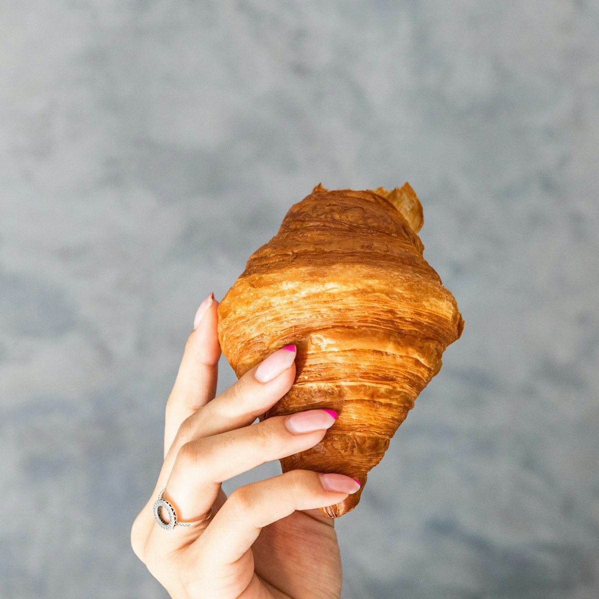 A baker holding a fresh croissant
