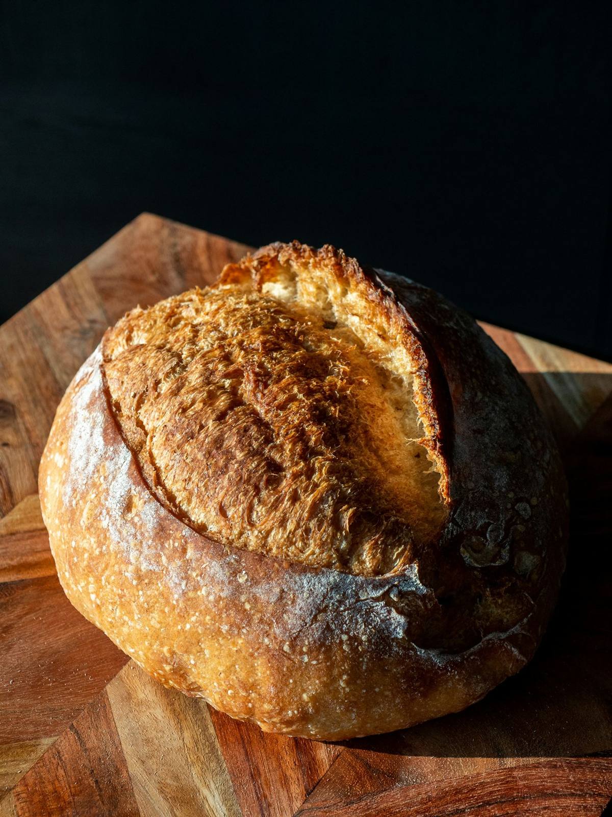 A crusty sourdough boule on a wooden board