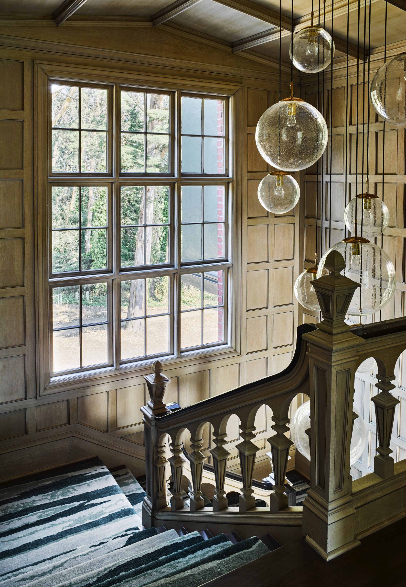 San Francisco Tudor stairwell with leaded window and glass pendants by Hillary Thomas