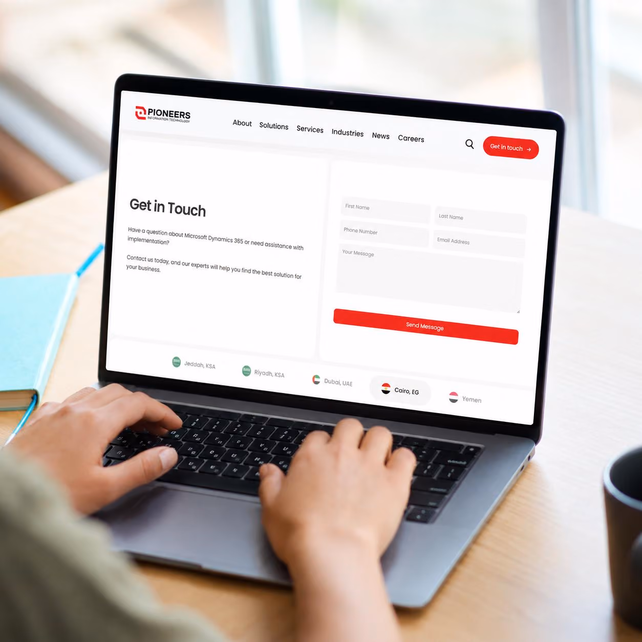 Person typing on laptop showing Pioneers IT contact form with fields for name, number, email, and message.