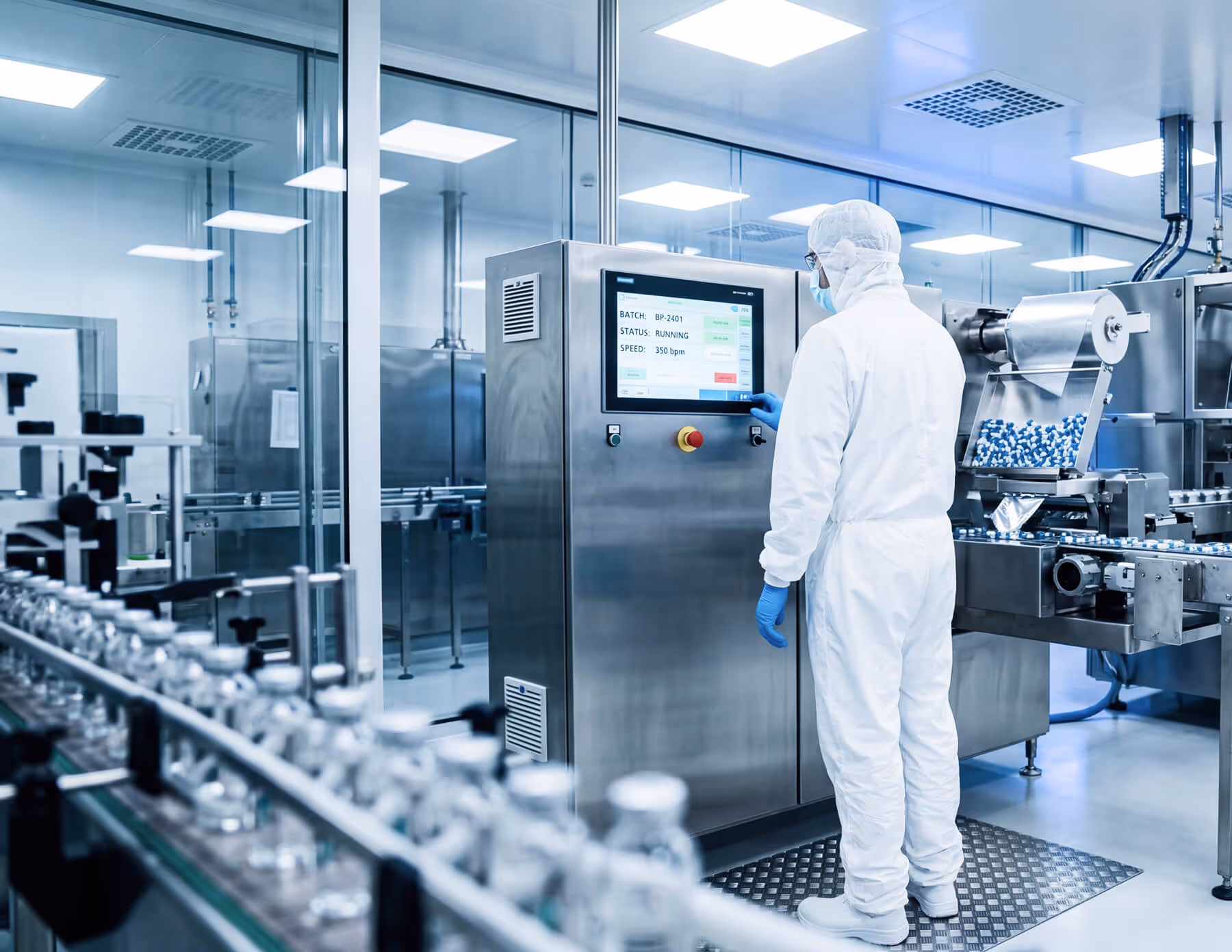 Technician operating automated pharmaceutical capsule production line inside a cleanroom.