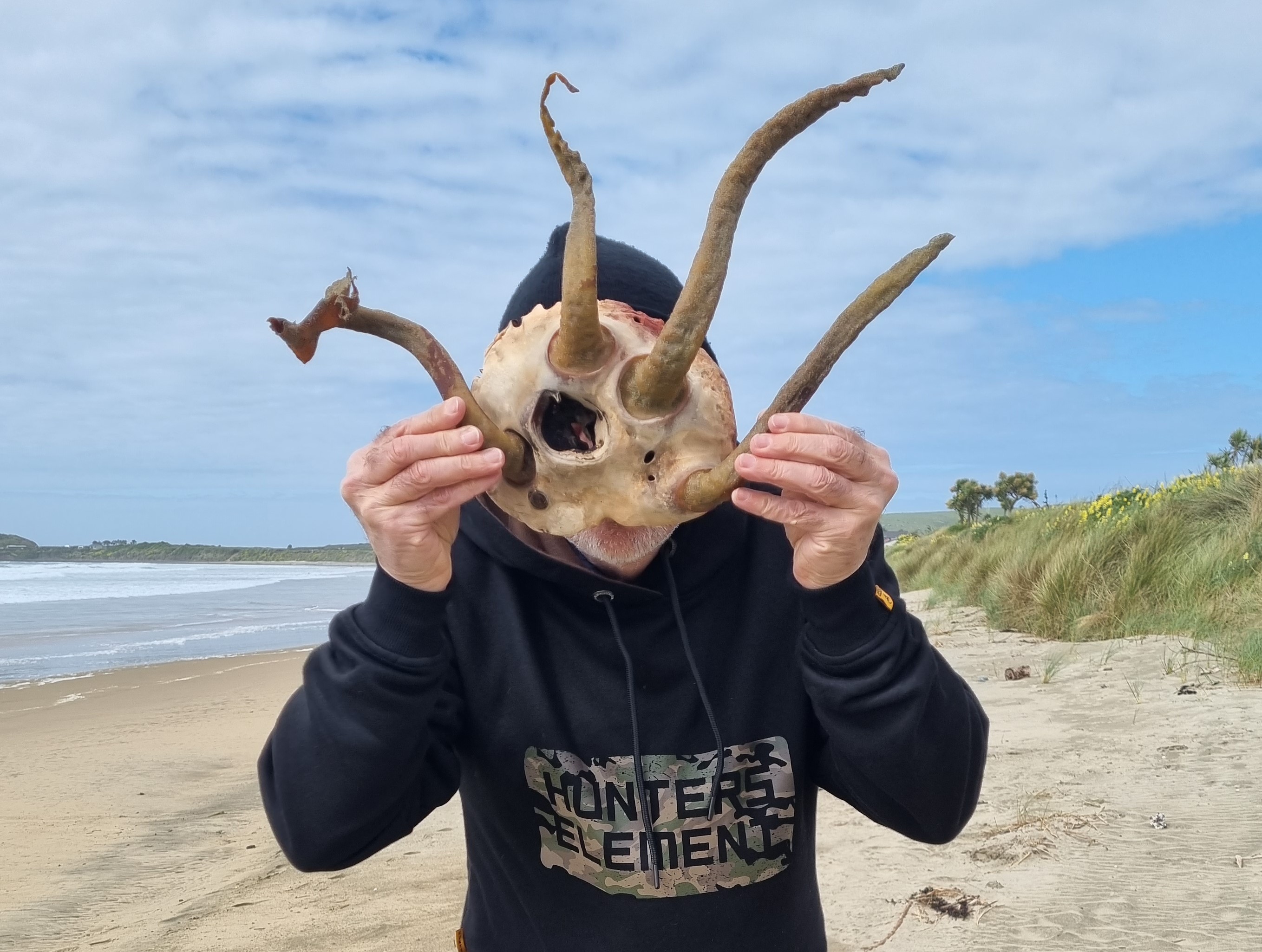 Wayne on a beach holding driftwood antlers