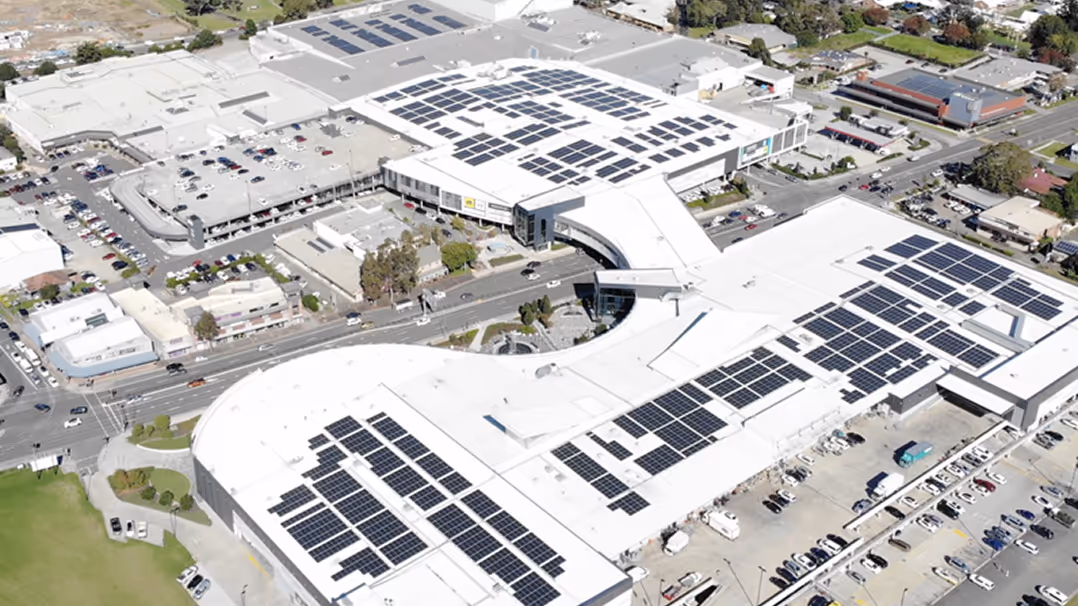 Aerial view of a commercial building complex with extensive rooftop solar panel coverage.