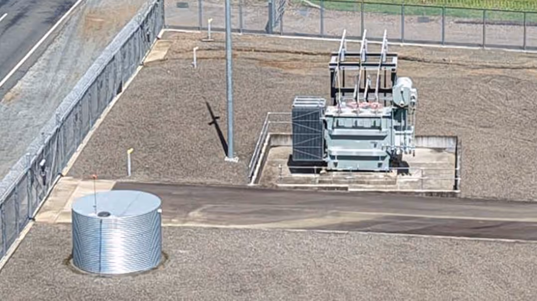 Electrical substation equipment including transformers and a cylindrical storage tank at an energy facility.