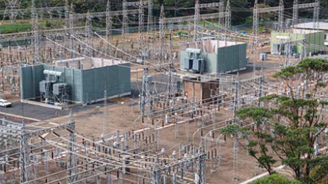 Industrial electrical infrastructure with transformers, switchgear, and storage tanks at an energy facility.