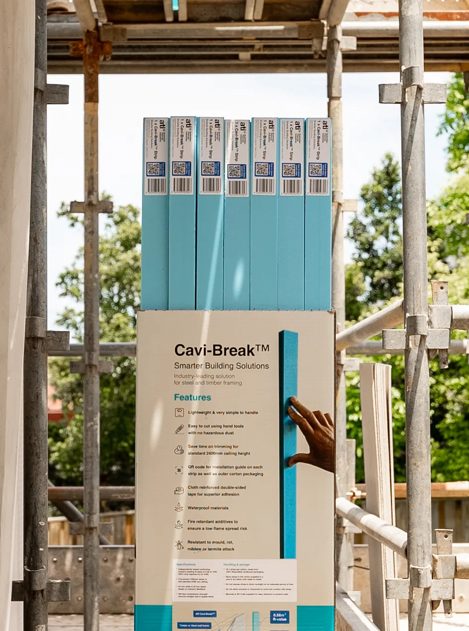Hand holding a blue Cavi-Break strip from a packaging box describing features of the smarter building solution for steel and timber framing.