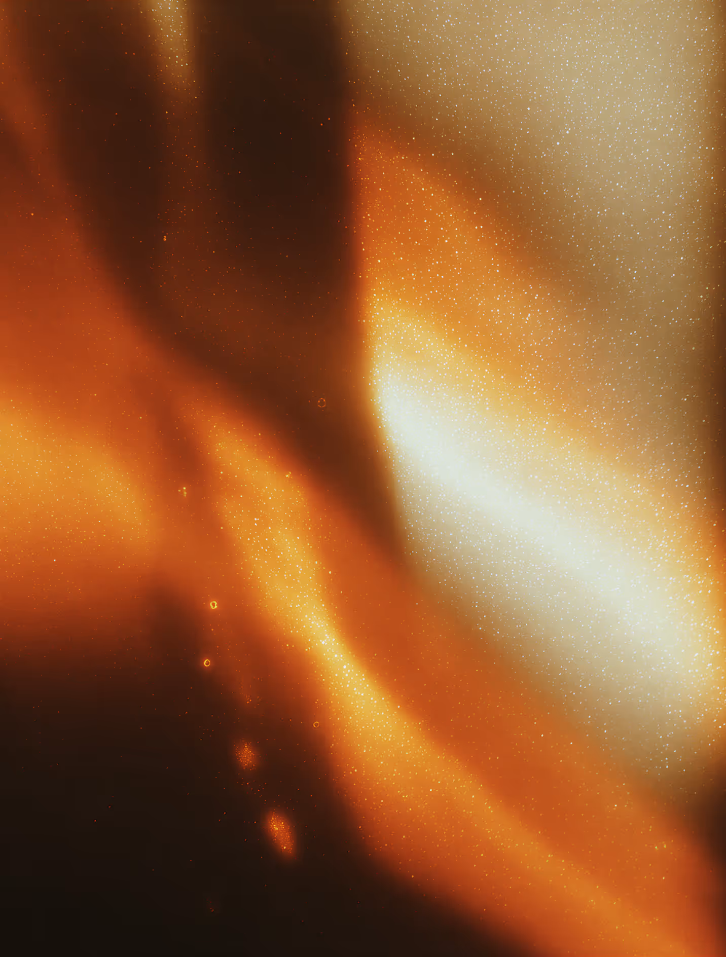 Abstract orange and golden light pattern with soft gradients and small glowing particles.