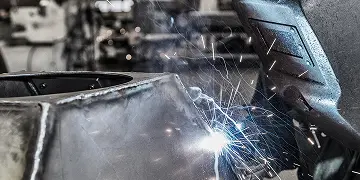 Close-up of a welding process with sparks flying from metalwork in a workshop.