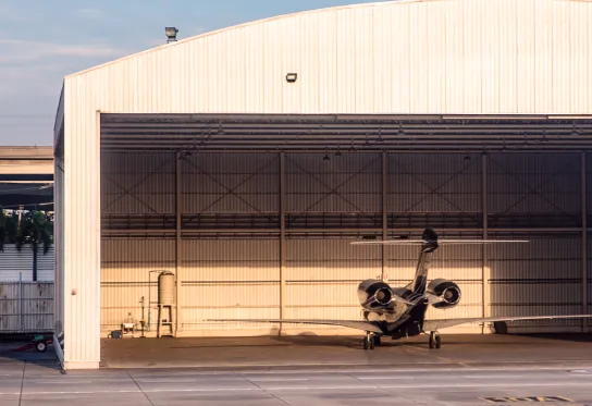 Small private jet parked inside an open hangar 