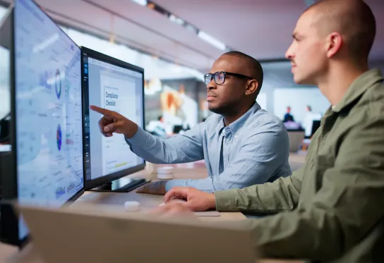 Two men at desks looking at computer screens