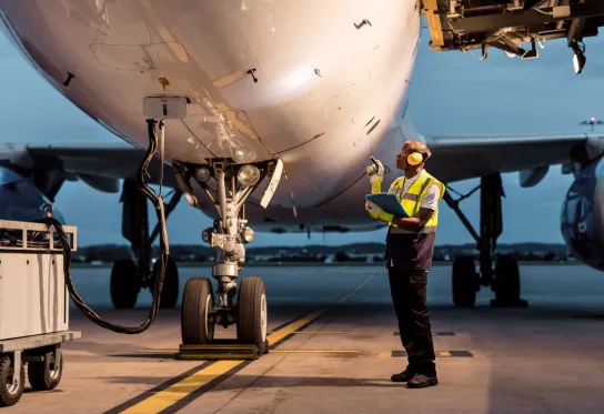 Airport ground crew member inspects airplane 