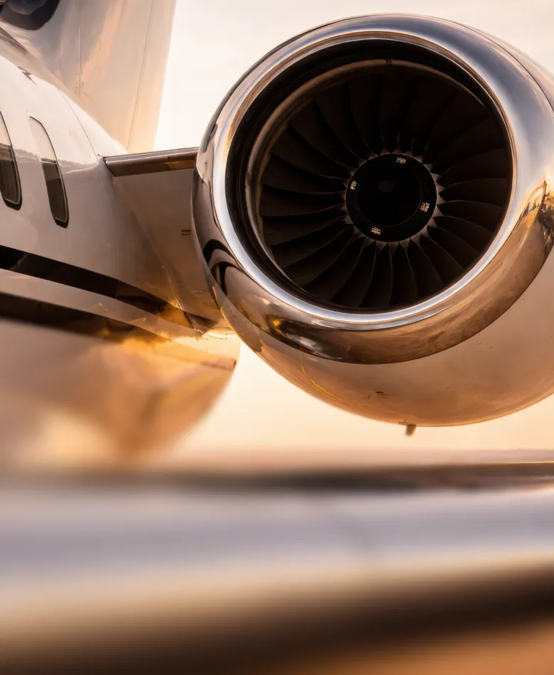 Close-up of a small aircraft's propeller, nose gear, and part of the wing on a runway.