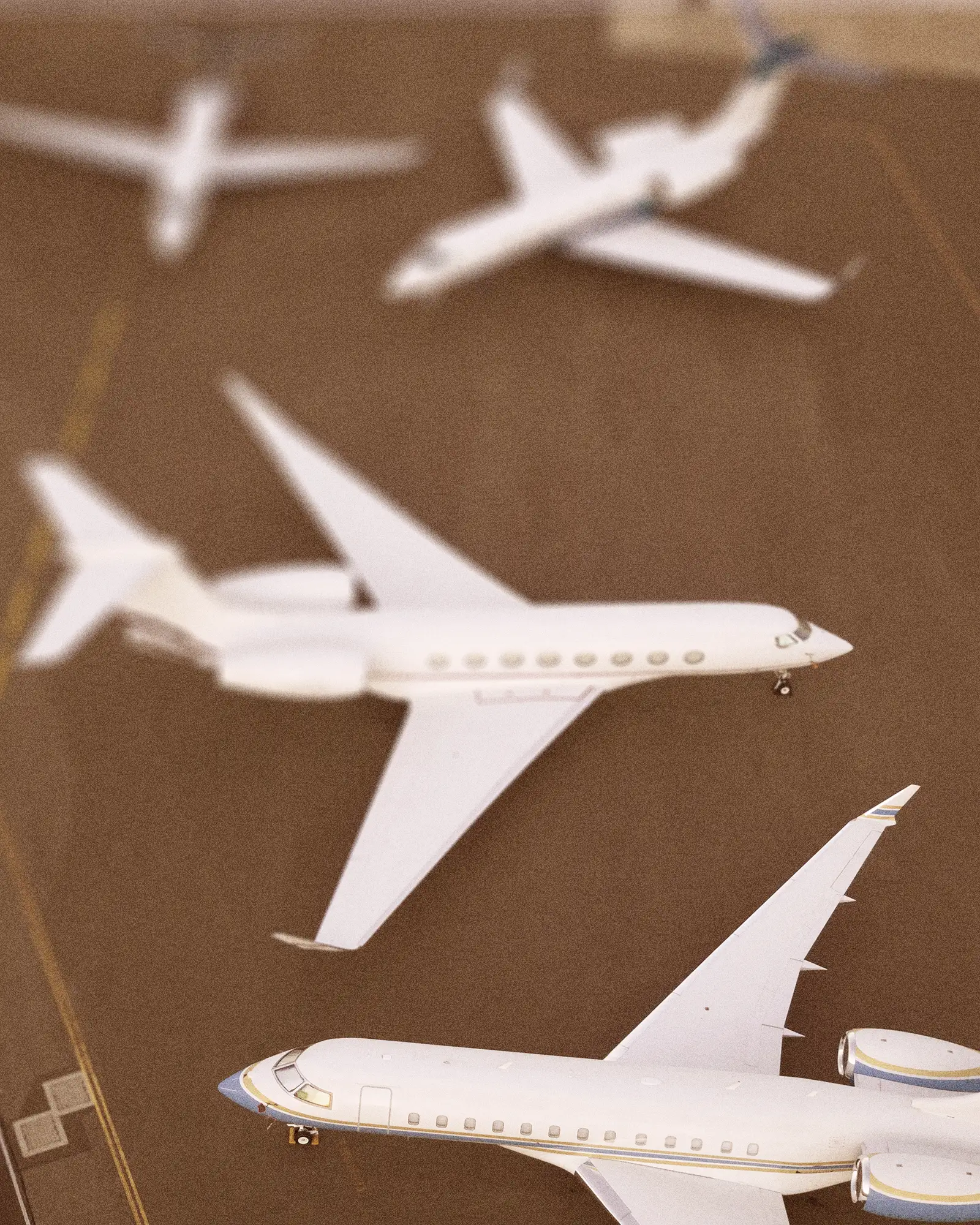 Aerial view of four white private jets parked on a tarmac at an airport.
