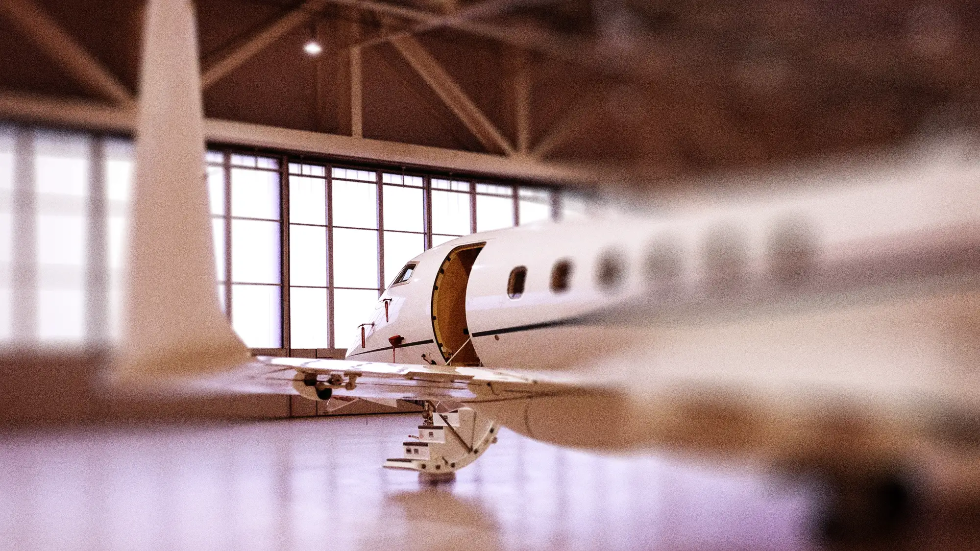 Private jet parked inside a hangar with its door open and stairs extended.