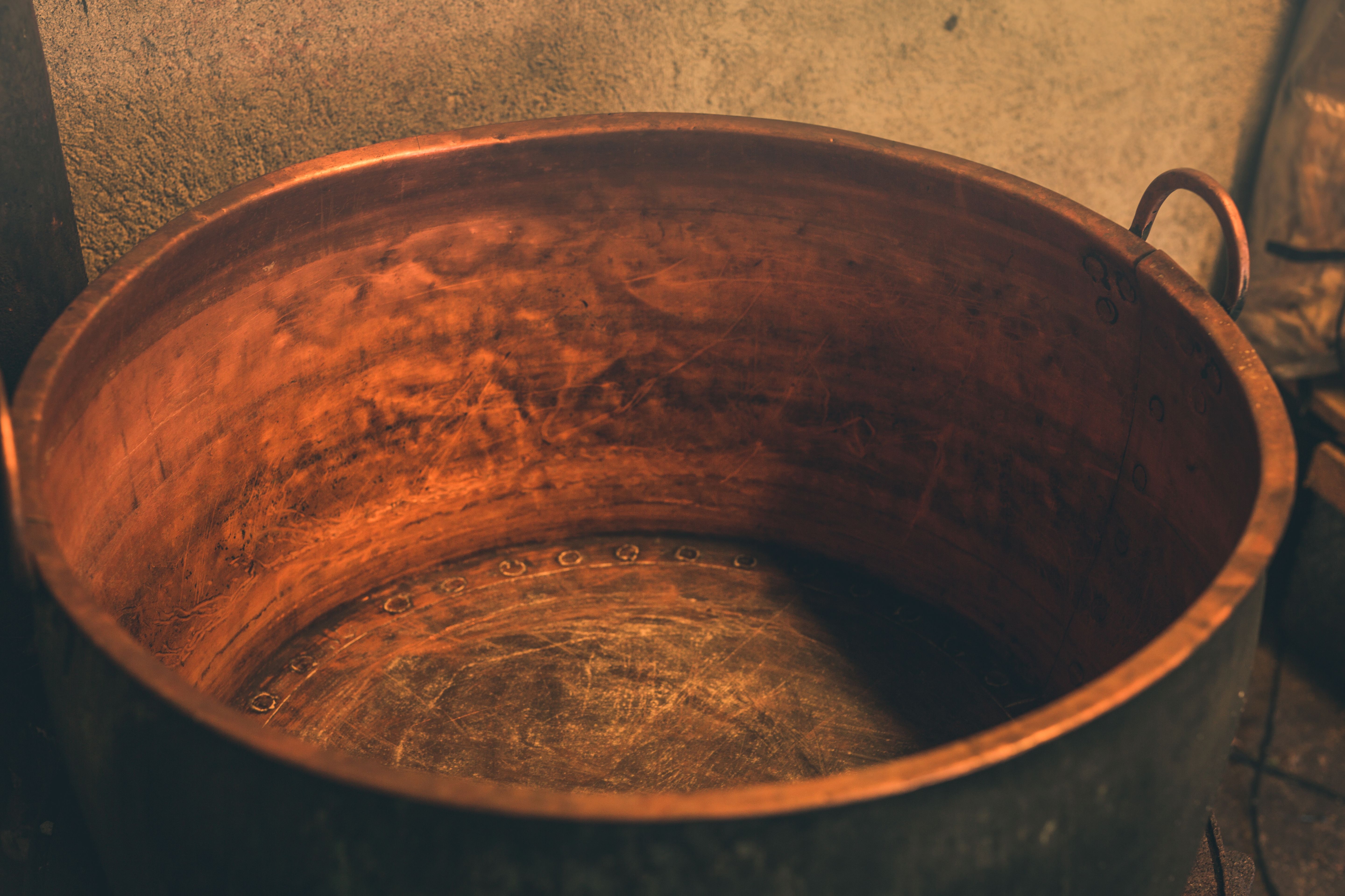 Large vintage copper cauldron with visible rivets and patina inside.
