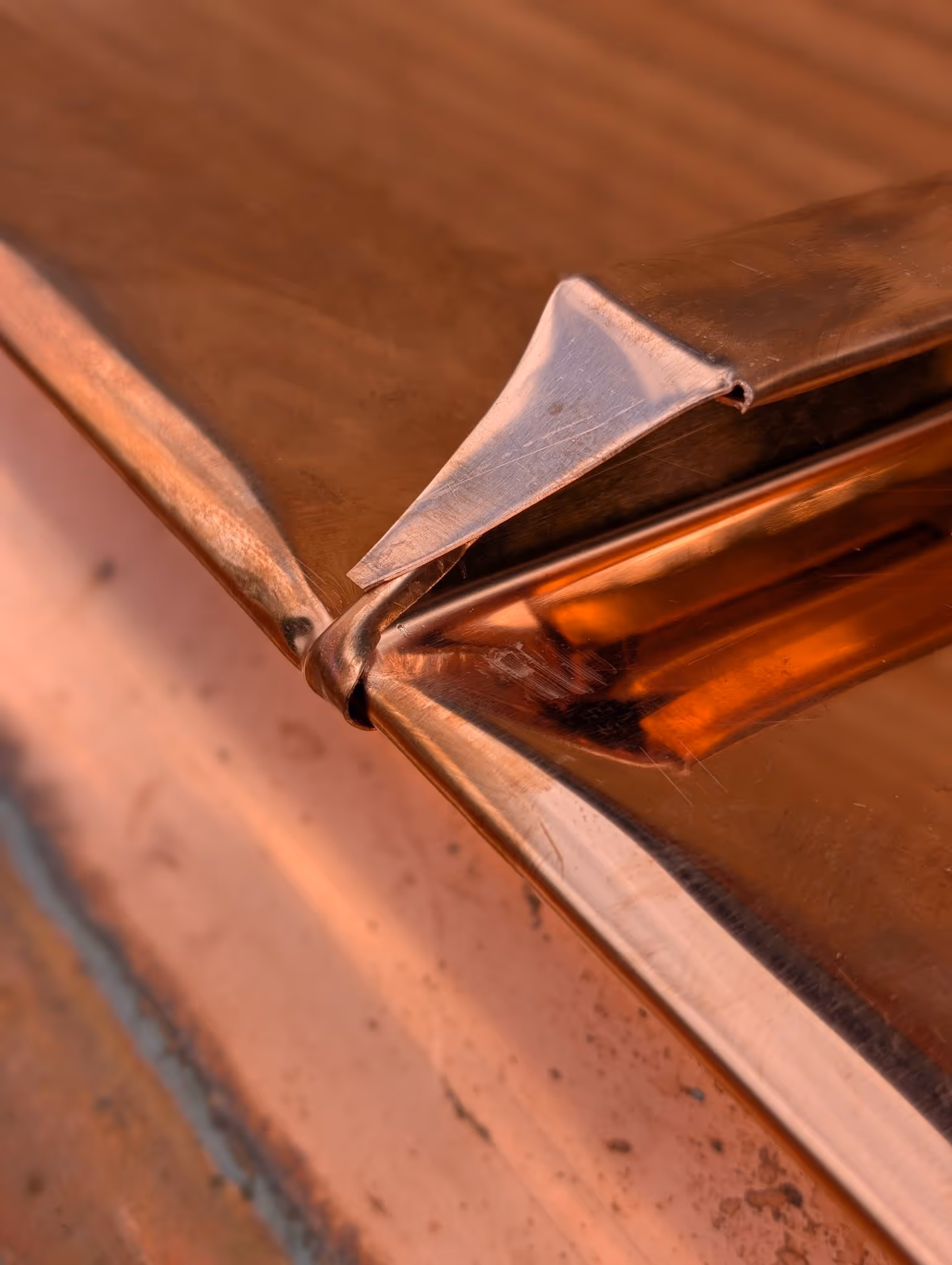 Nahaufnahme einer kupferfarbenen Metallkante mit gebogenem Metallstreifen.