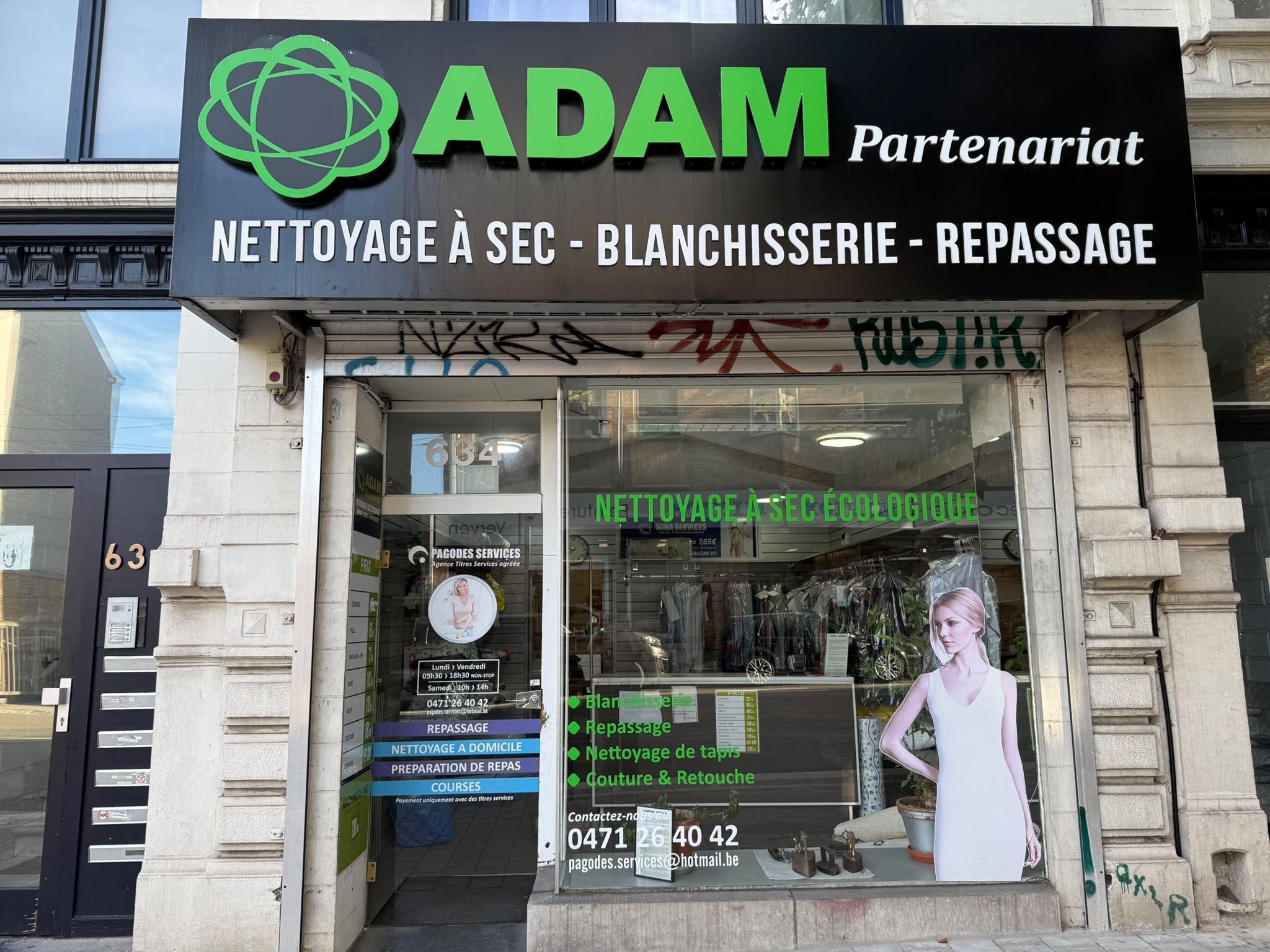 Devanture d'une boutique de vêtements élégante avec une femme examinant un vêtement à l'intérieur.