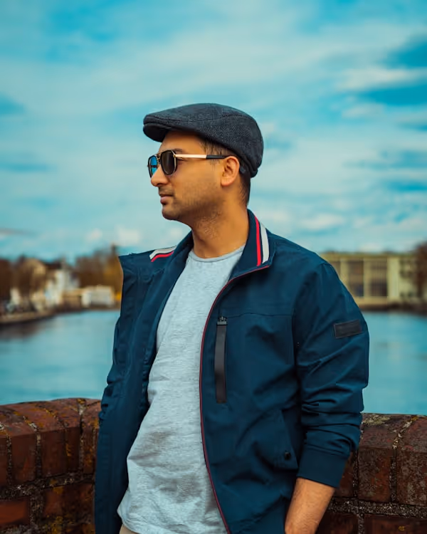 Man wearing a flat cap and sunglasses by water