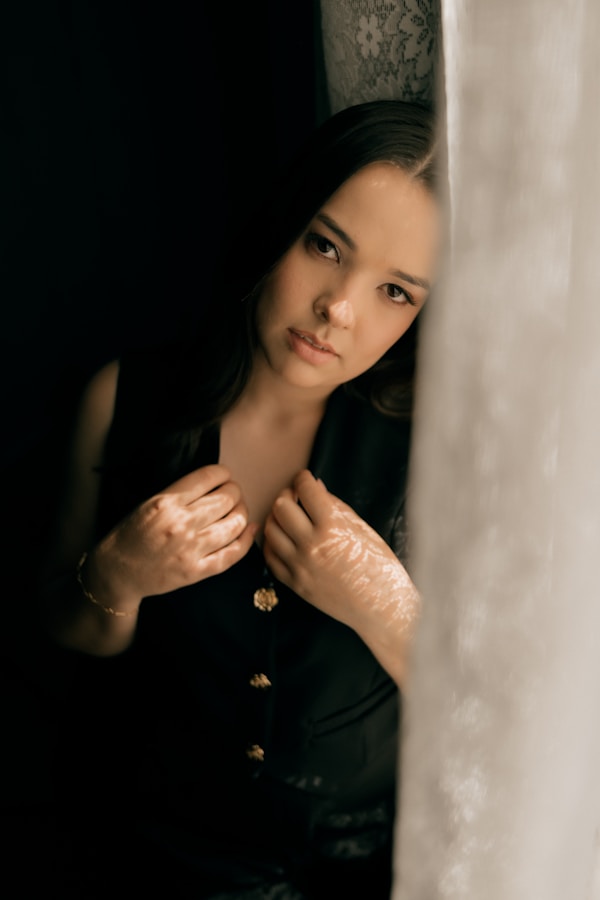 Young woman in black vest leans against window