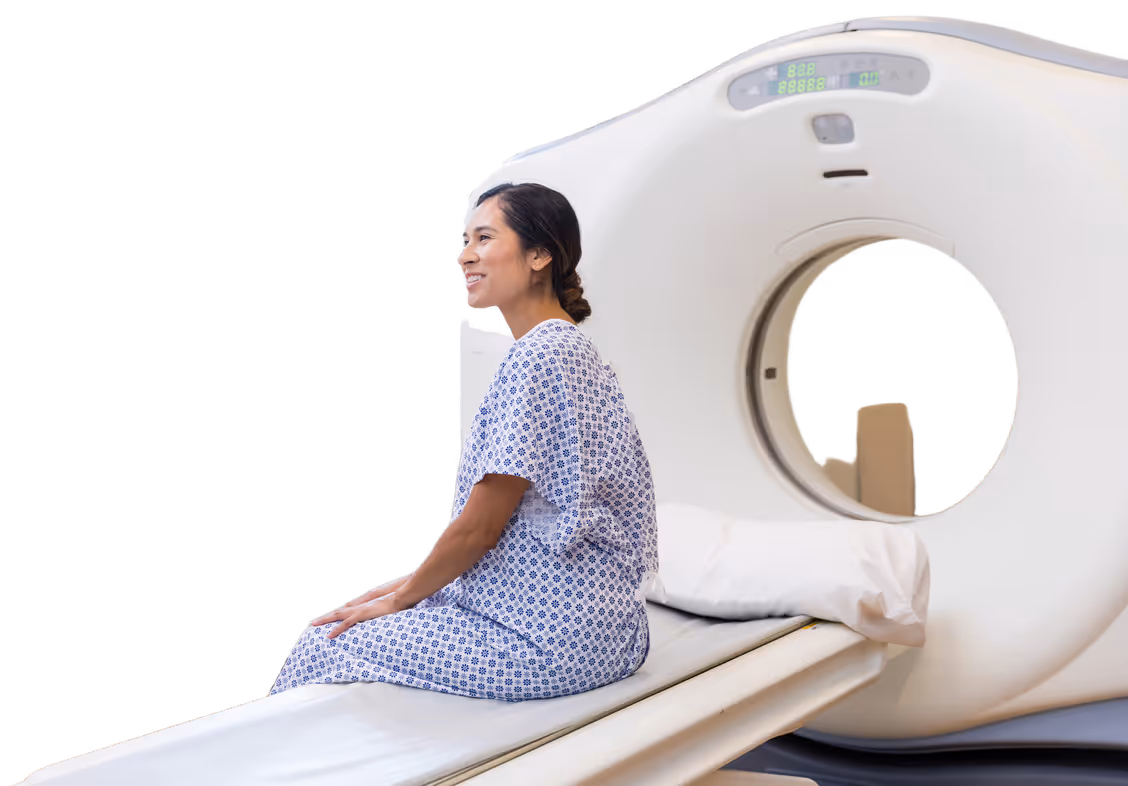 Patient sitting on a medical scanner table wearing a hospital gown, ready for a scan.