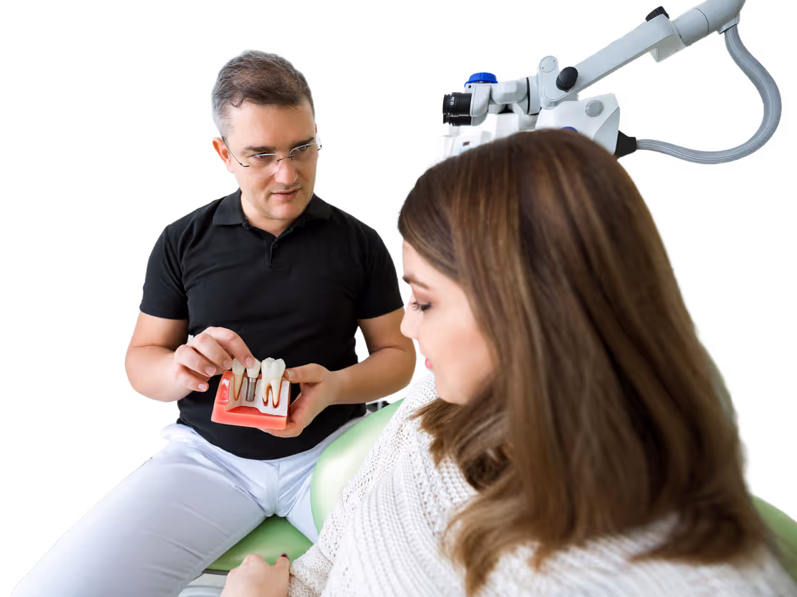 Dentist explaining dental implants using a tooth model to a patient in a dental chair.