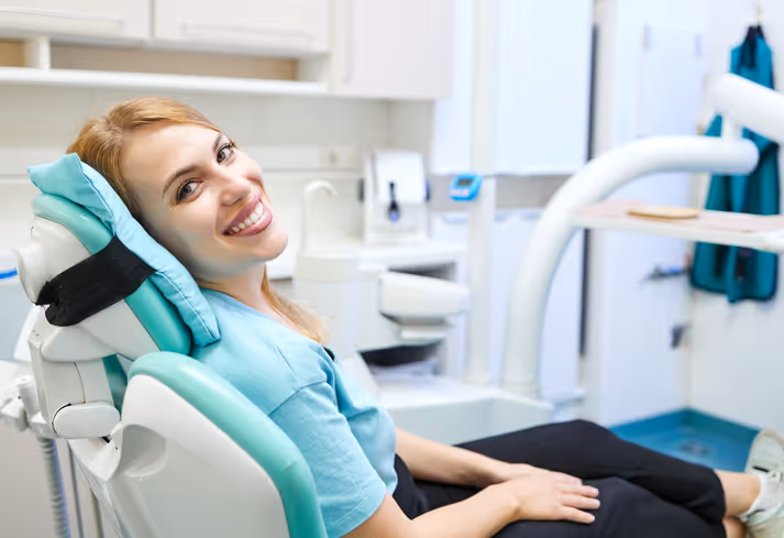 Smiling woman reclining in a dental chair in a bright dentist office.