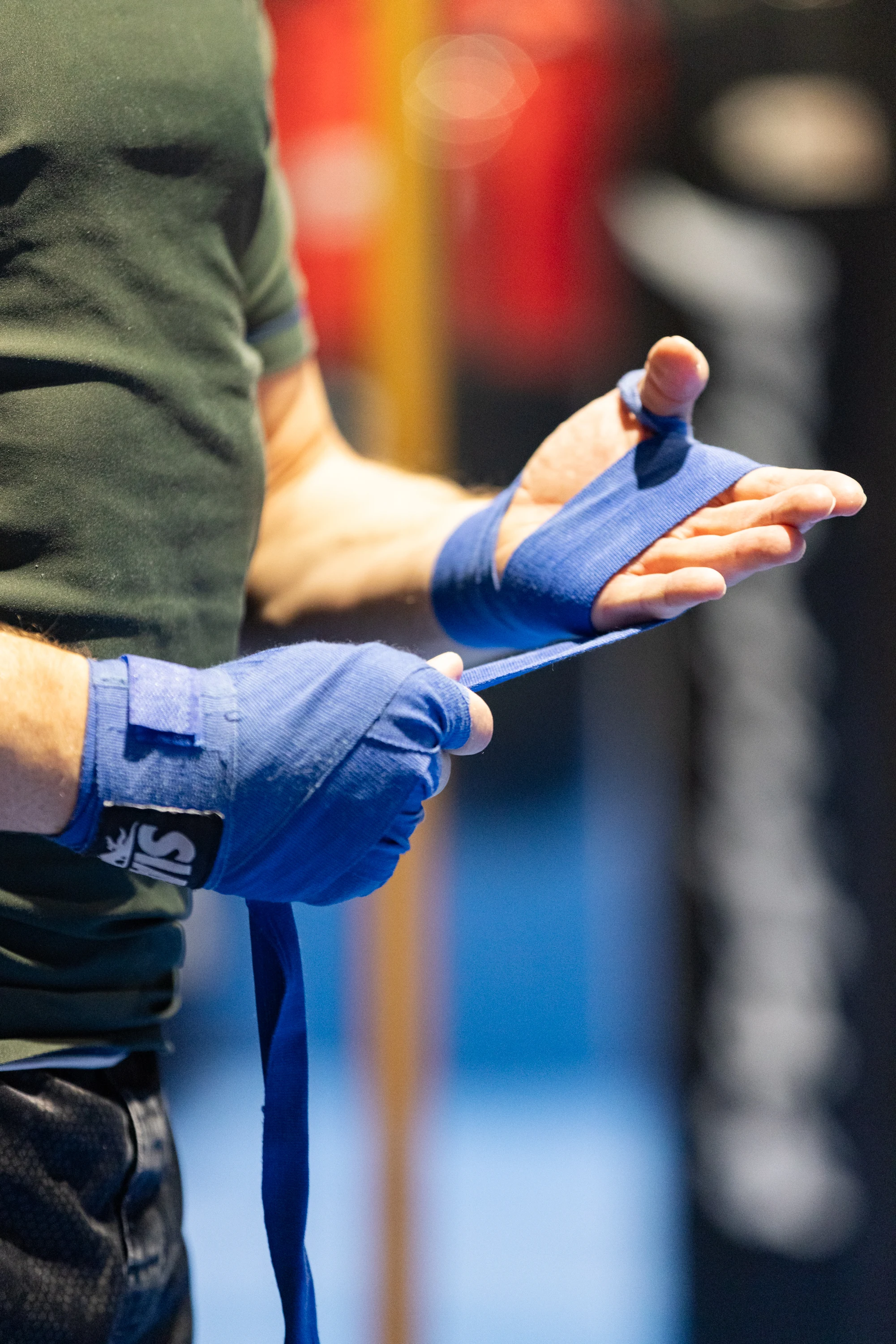 Person wrapping blue hand wraps around their hands, preparing for boxing or martial arts training.