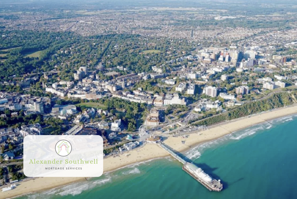 Aerial view of a coastal town with beach, pier, green parks, and a densely built urban area.